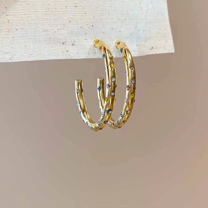 Vue détaillée des boucles d'oreilles créoles dorées en C ornées de zircons multicolores