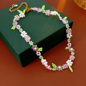 Close-up of handmade floral bead necklace with pink and purple beads on jewelry box