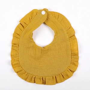 Detail of ginger yellow ruffled baby bib made from breathable cotton crepe with snap button