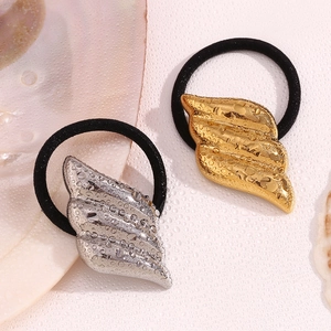 Detail of 18K gold and silver wing-shaped charms with water droplets on elastic hair ties