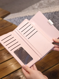 Detailed interior view of a pink PU leather long wallet with multiple card slots on wood