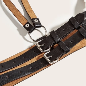 Detailed close-up of punk style black leather harness belt with metal buckles and rings