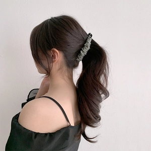 Detail of army green pleated fabric banana clip styling a ponytail on a model