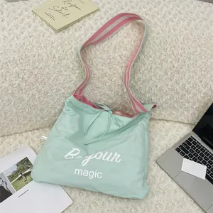 Vue détaillée du sac cabas vert menthe avec bandoulière rayée sur un fond en polaire douce