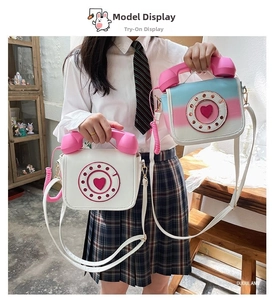 Detail of creative telephone-shaped crossbody bag featuring heart dial and retro handset