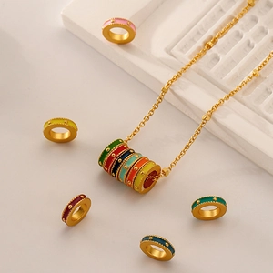 Golden chain necklace with colorful enamel rings and textured metal beads on a beige backdrop