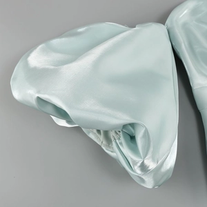 Close-up of light green satin lantern sleeves showing glossy fabric texture and puff detail