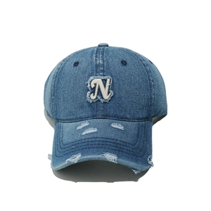 Detailed view of distressed denim baseball cap with vintage frayed letter N patch