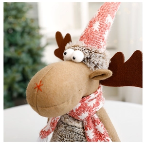 Close-up of brown plush Christmas reindeer doll with red knitted hat and warm scarf