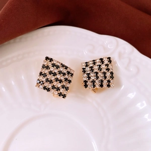 Luxurious geometric checkerboard stud earrings with crystals on a ceramic dish
