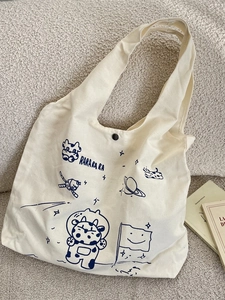 Large off-white canvas tote bag featuring a navy blue astronaut cow print and snap button