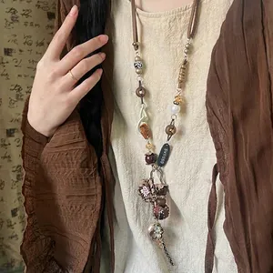 Macro view of boho multi-material pendant necklace with fabric flower and wooden beads
