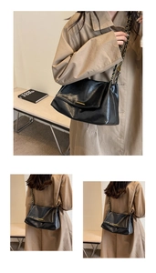 Detail of black glossy leather tote bag with gold metal buckle and chain strap