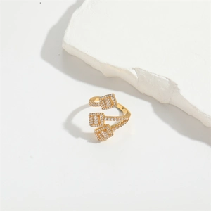 Macro detail of gold-plated ring featuring three tiered square settings with clear gemstones