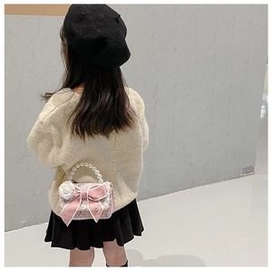 Detailed back view of a child modeling a pink tweed mini bag with bow and pearl handle