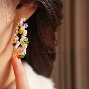 Macro detail of colorful crystal beads and pearls on large golden vintage hoop earrings