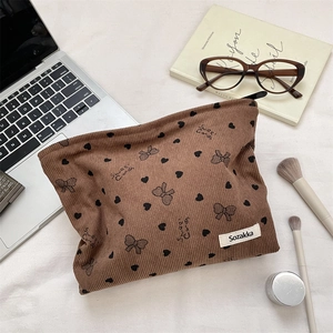 Borsa cosmetica in velluto a coste marrone con cuori e fiocchi su una scrivania