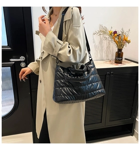Detail of black quilted down cotton shoulder bag with adjustable strap and top handle