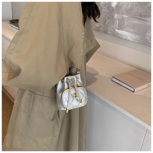 Detailed side view of silver quilted drawstring bucket bag with golden camellia flower