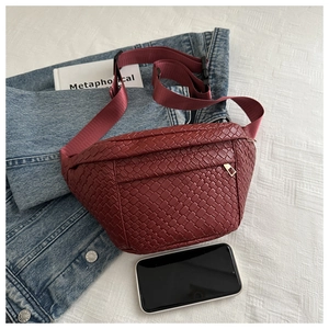Detail of dark red woven belt bag with nylon strap shown next to a smartphone for scale