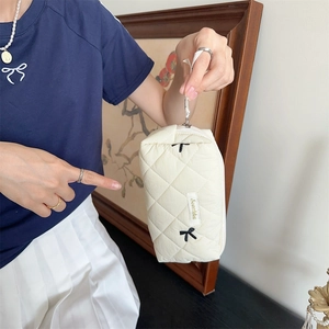Detail of quilted cream makeup bag with black bow embroidery and gold Svetka tag