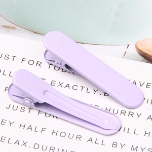 Detail of two lavender purple matte metal duckbill hair clips on decorative paper card