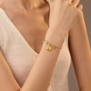 18k gold plated stainless steel bracelet with shell, starfish and turquoise charms on wrist