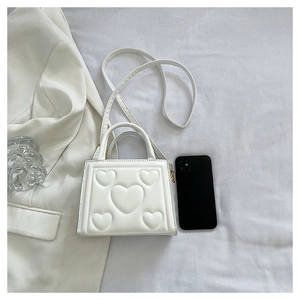 Gros plan d'un sac à main rectangulaire blanc avec motif de cœur matelassé en relief