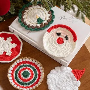 Handmade knitted Christmas coasters featuring Santa and snowflake designs on wooden table