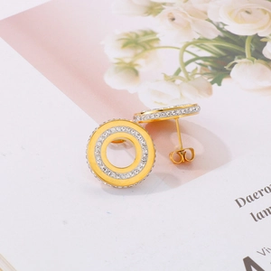 Close-up of gold pavé-set round stud earrings with hollow center and clear crystals