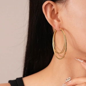 Close-up of a model wearing layered gold hoop earrings with a bold geometric design