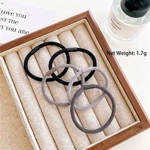 Set of 4 high elasticity black and grey hair ties with 5cm diameter on a wooden tray