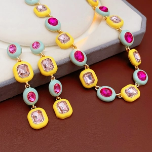 Detail of luxury vintage gold earrings and necklace with pink crystal and colorful enamel