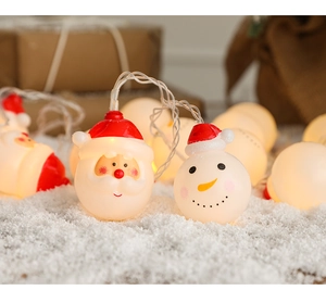 Close-up of Santa and snowman LED string lights glowing on soft artificial snow surface