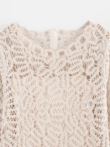 Gros plan du haut en crochet beige montrant les motifs ajourés et les détails du col
