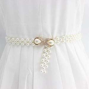 Detail of pearl waist chain with rhinestone bow buckle on white dress for women