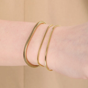 Trois variantes de bracelets à chaîne serpent en acier doré sur un poignet