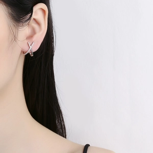 925 sterling silver X-shaped diamond stud earring on model ear in a minimalist style