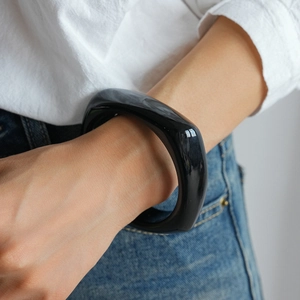 Close-up of a minimalist black acrylic geometric square bangle on a model's wrist