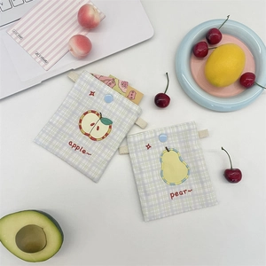 Flat lay of cotton checkered pouches with embroidered apple and pear designs and snap buttons