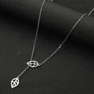Detail shot of silver leaf pendant necklace featuring intricate hollow and solid engravings