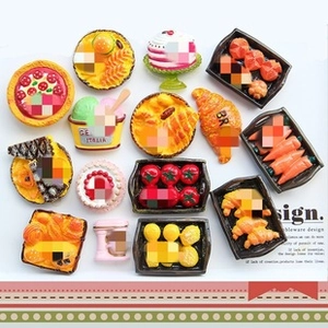 Flat lay macro of assorted miniature food magnets including pizza, croissants and cakes