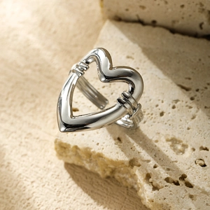 Close-up of silver hollow heart ring with triple-band design on stone texture
