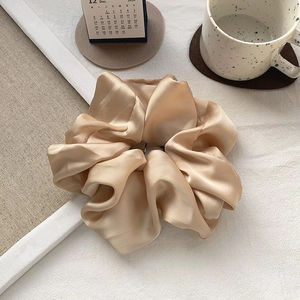 Close-up of champagne gold satin hair scrunchie showing silky texture and smooth gloss