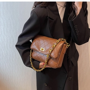 Detail of brown quilted leather bag with gold chain strap and turn-lock closure on model
