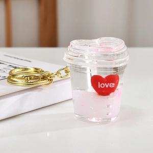 Detail of pink heart-shaped liquid keychain with glitter and gold metal ring