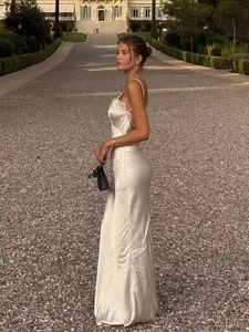 Elegant white satin maxi dress with lace detailing shown in a scenic garden outdoor setting
