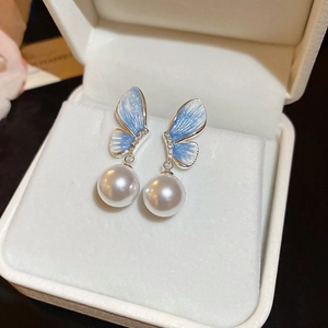 Details von silbernen Ohrhänger mit blauen Schmetterlingsflügeln und weißen Perlen
