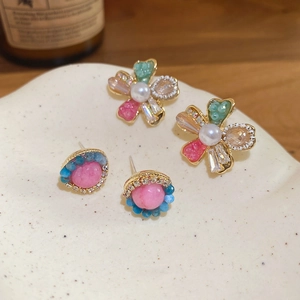 Floral crystal stud earrings with faux pearls and gems on a ceramic tray display