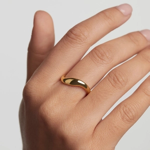 Minimalist irregular wave ring in polished gold finish worn by a model on plain background